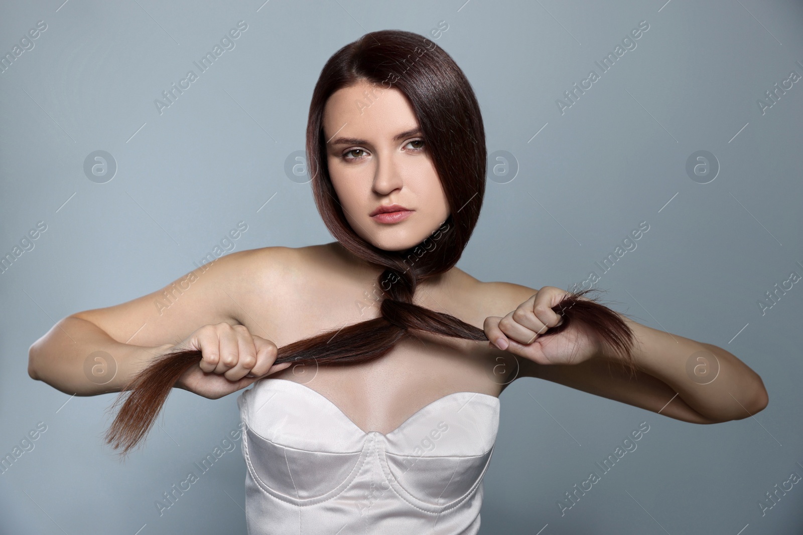Photo of Portrait of beautiful young woman with healthy strong hair on light gray background