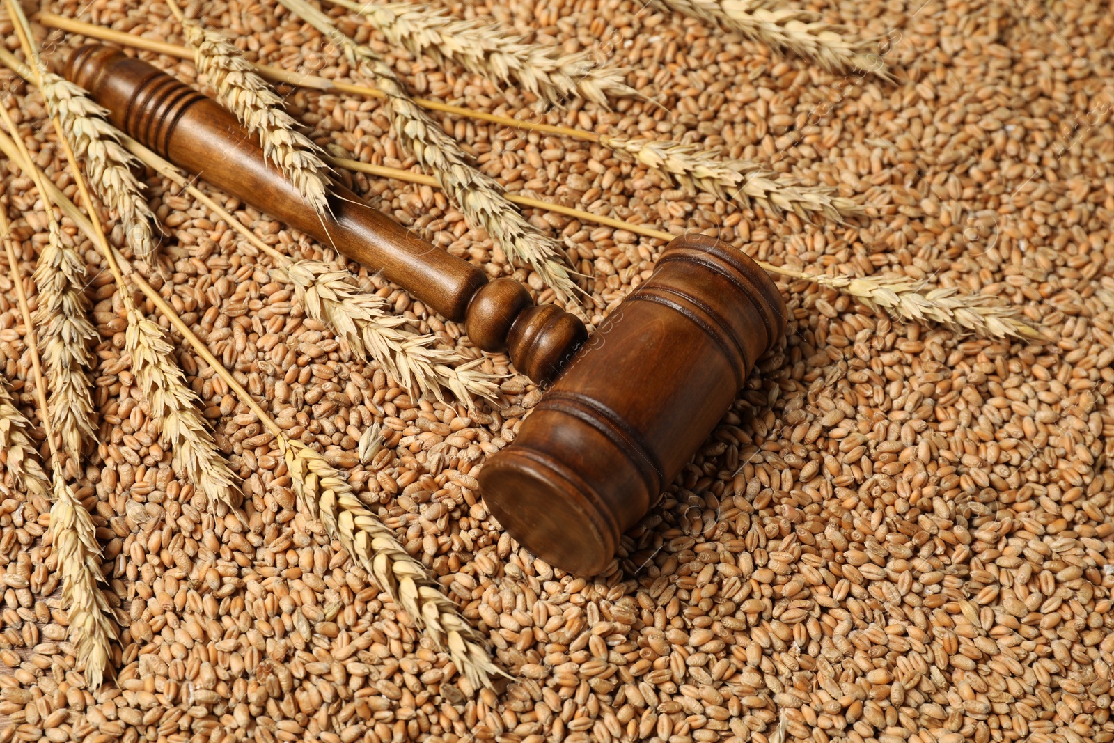 Photo of Wooden gavel and wheat ears on grains. Agricultural deal