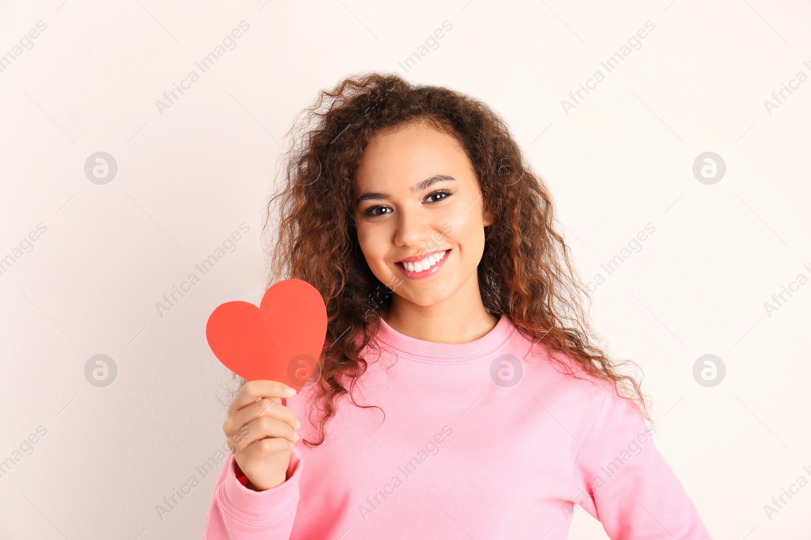 Photo of African-American woman with paper heart on white background