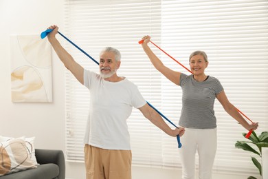 Photo of Senior couple doing exercise with fitness elastic bands at home