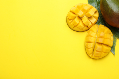 Cut fresh ripe mango and leaves on yellow background, flat lay. Space for text