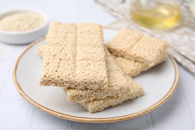 Photo of Plate with delicious sesame kozinaki bars on white table, closeup