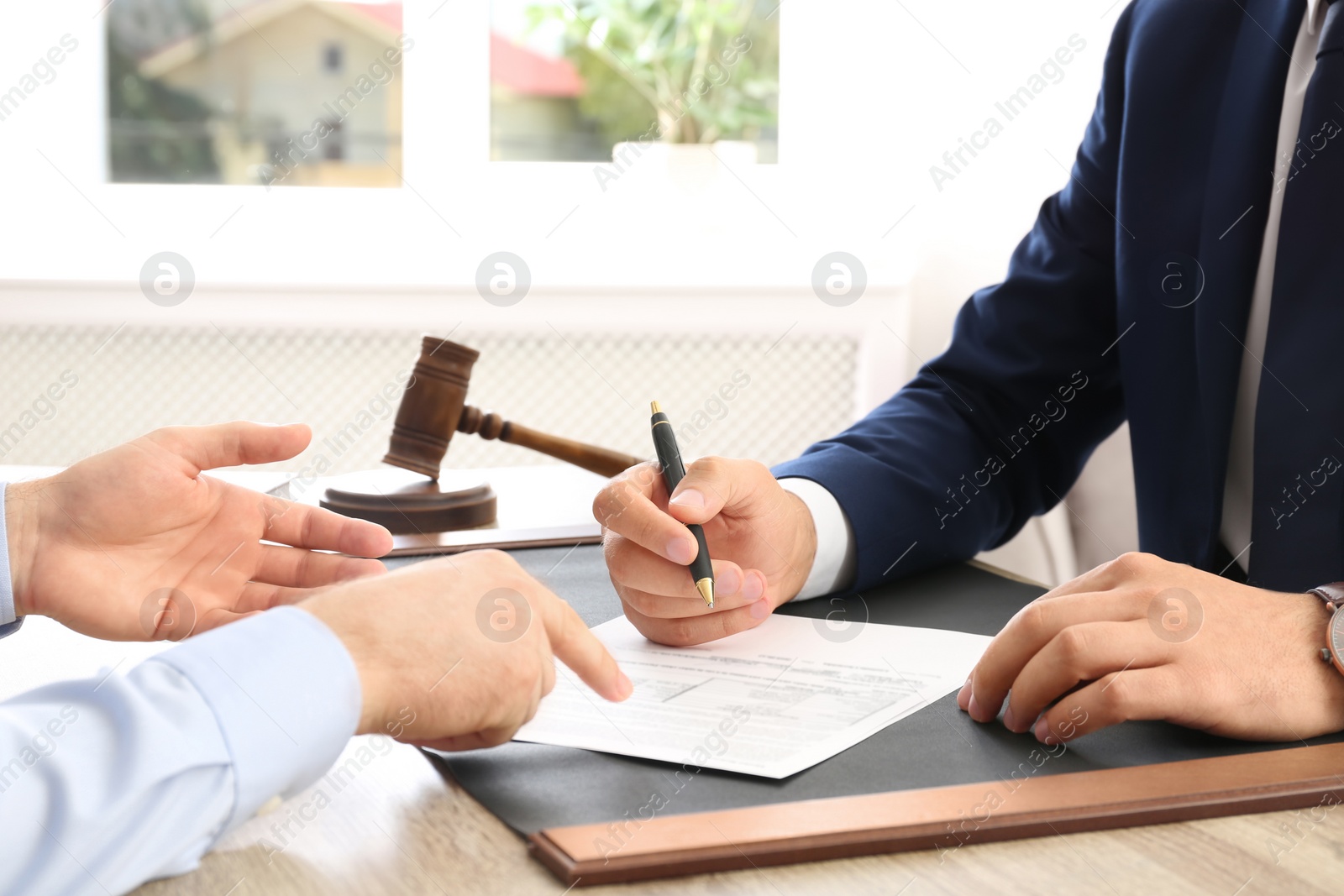 Photo of Lawyer working with client at table in office, focus on hands