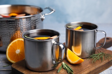 Photo of Tasty mulled wine with spices in mugs on wooden table