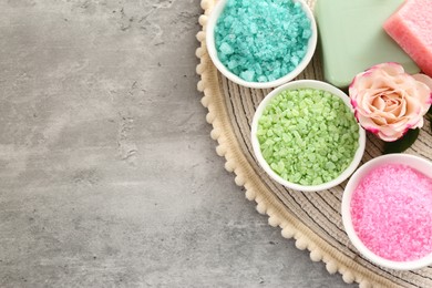 Photo of Different types of aromatic sea salt and beautiful flower on grey textured table, top view. Space for text