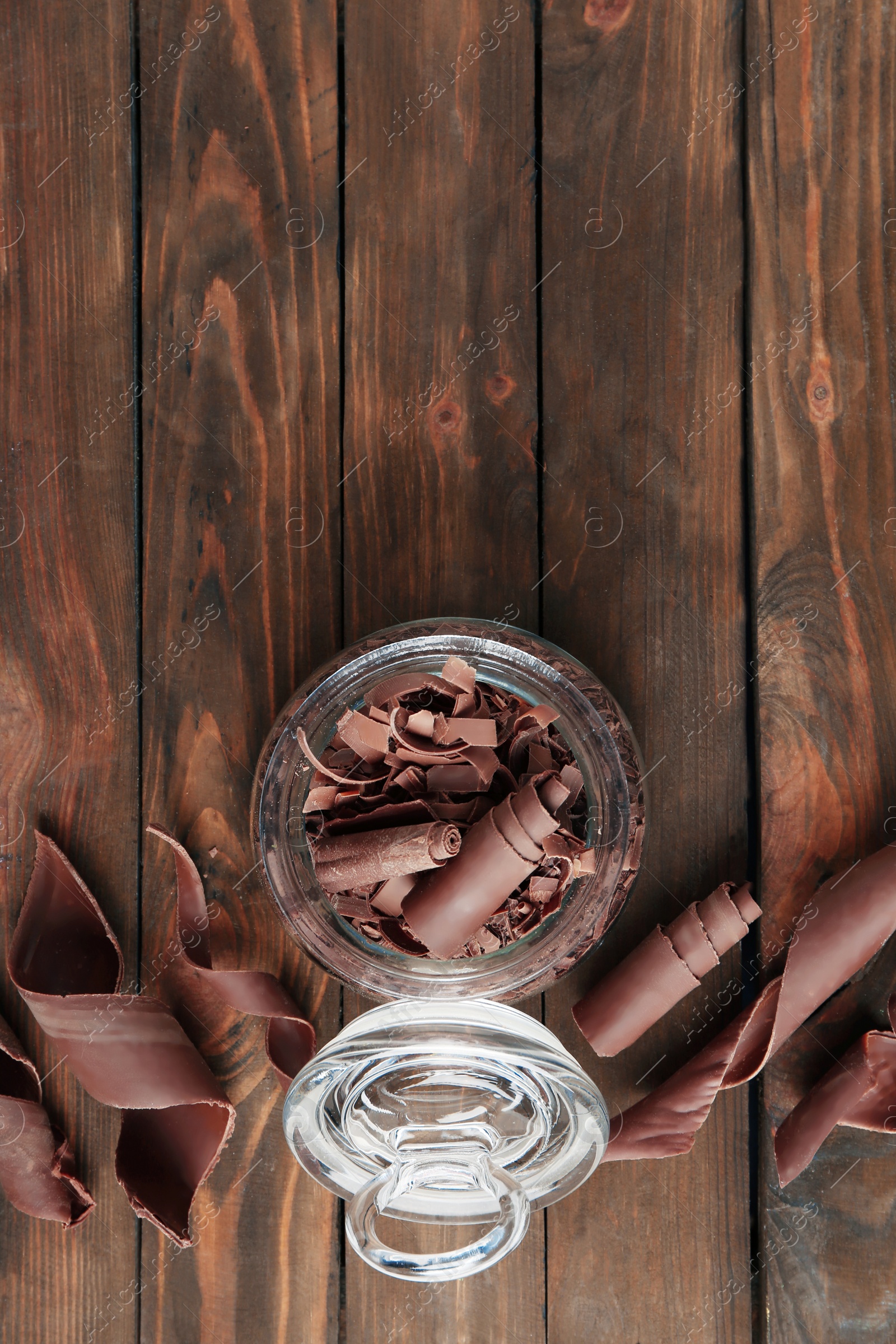 Photo of Flat lay composition with jar of chocolate curls on wooden background. Space for text