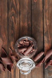 Flat lay composition with jar of chocolate curls on wooden background. Space for text