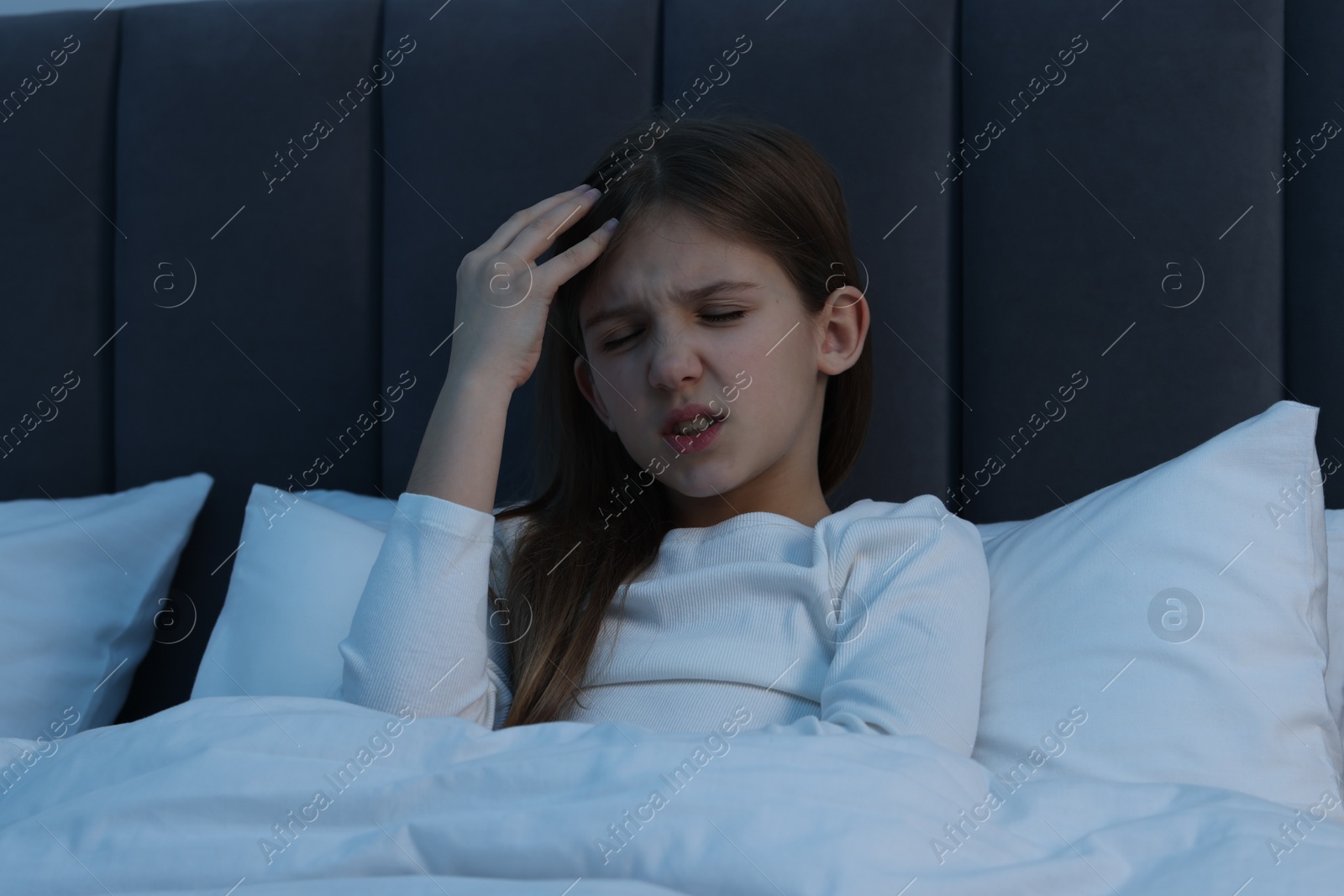 Photo of Little girl suffering from headache in bed at night