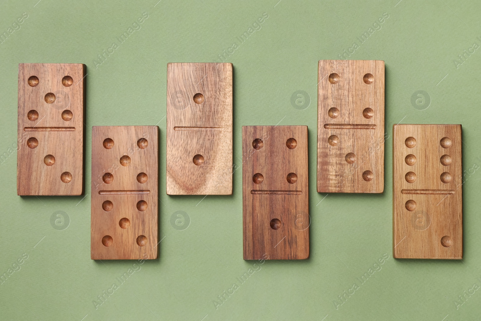 Photo of Wooden domino tiles on green background, flat lay