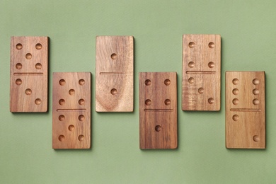 Photo of Wooden domino tiles on green background, flat lay