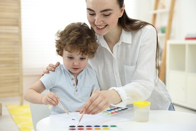 Mother and her little son painting with watercolor at home, closeup