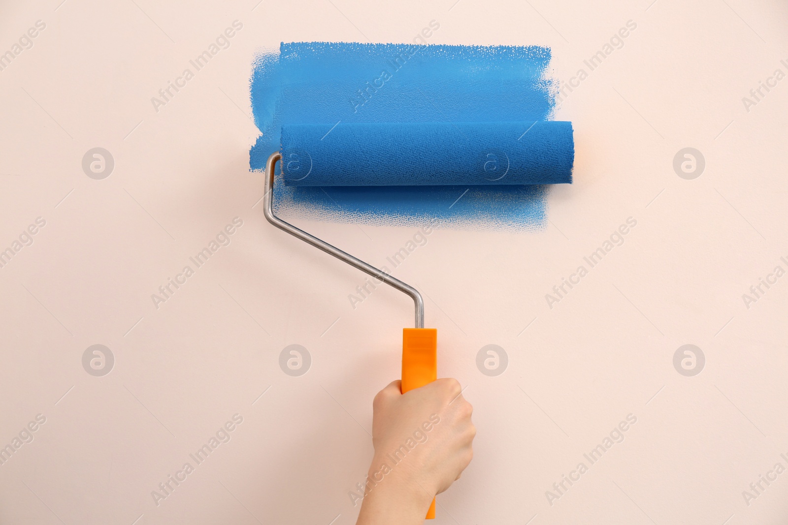 Photo of Woman painting wall with roller, closeup. Redecoration