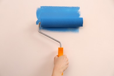 Photo of Woman painting wall with roller, closeup. Redecoration