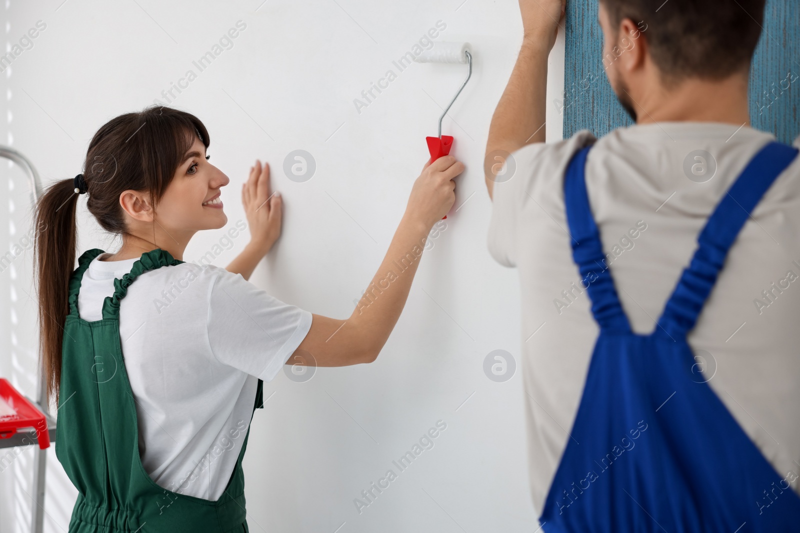 Photo of Workers hanging light blue wallpaper in room