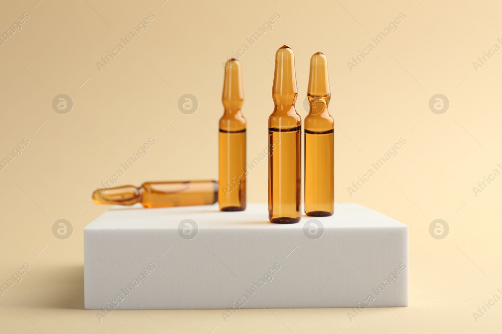 Photo of Glass ampoules with liquid on beige background