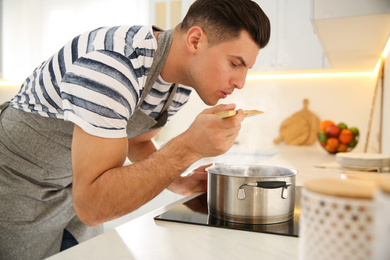 Photo of Handsome man cooking on stove in kitchen