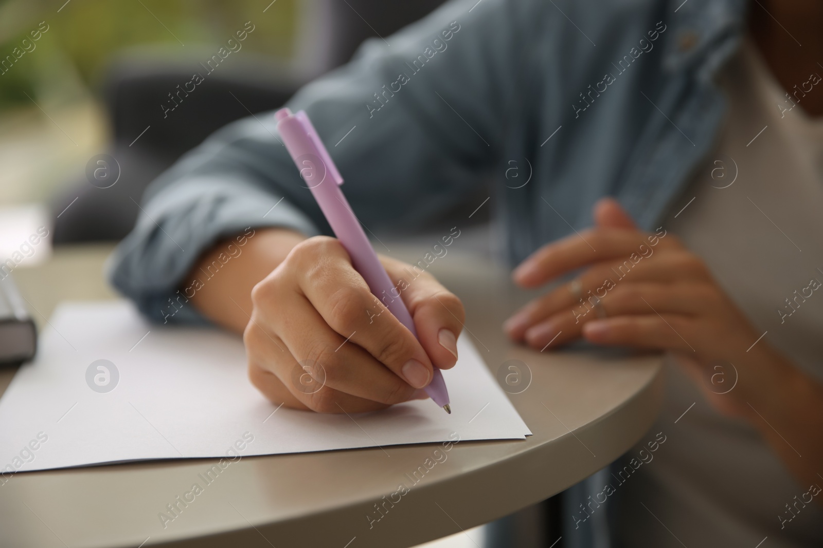 Photo of Woman writing letter at table indoors, closeup