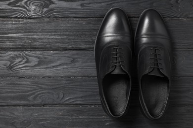 Photo of Pair of leather men shoes on black wooden background, top view. Space for text