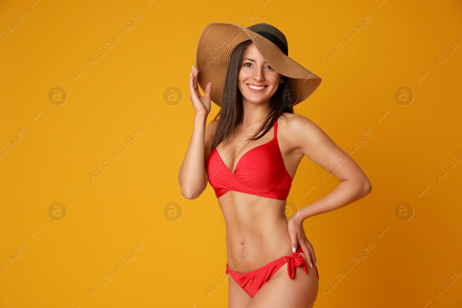 Photo of Pretty sexy woman with slim body in stylish red bikini on orange background, space for text