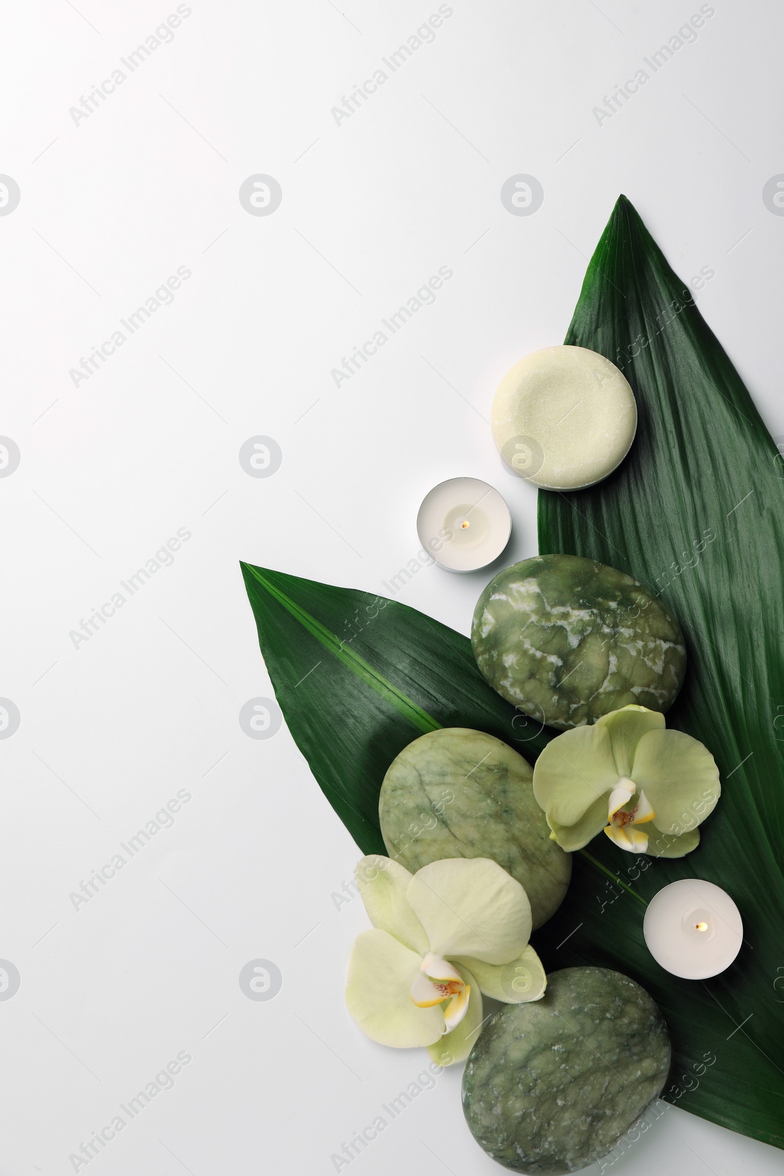 Photo of Flat lay composition with spa stones, solid shampoo bar and beautiful flowers on white table. Space for text