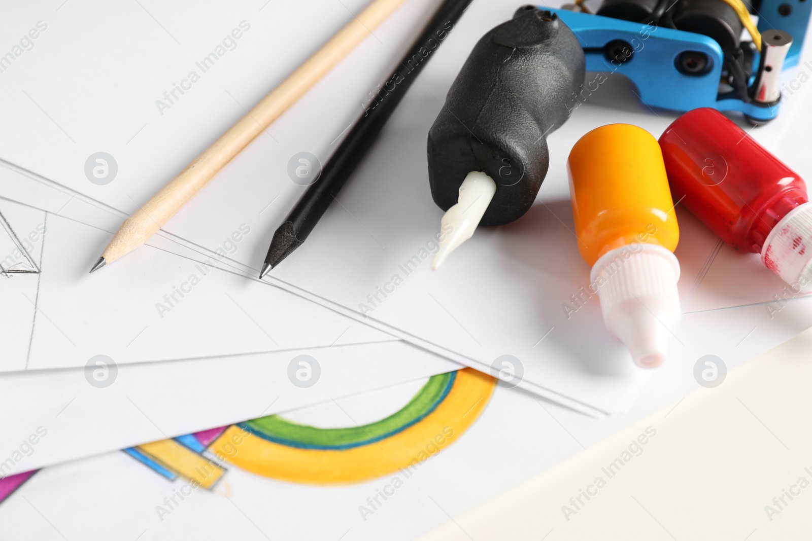 Photo of Composition with sheets of paper and tattoo machine on table