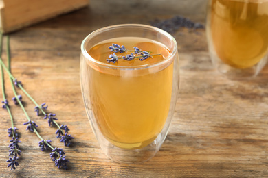 Photo of Fresh delicious tea with lavender in glass on wooden table