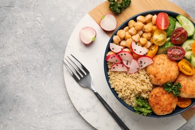 Delicious vegan bowl with chickpeas, cutlets and radish on grey table, top view. Space for text