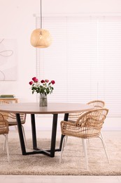 Photo of Chairs and table with vase of red rose flowers in dining room. Stylish interior