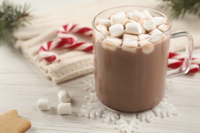 Photo of Hot drink with marshmallows in glass cup on white wooden table