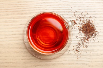 Photo of Freshly brewed rooibos tea and scattered dry leaves on wooden table, flat lay