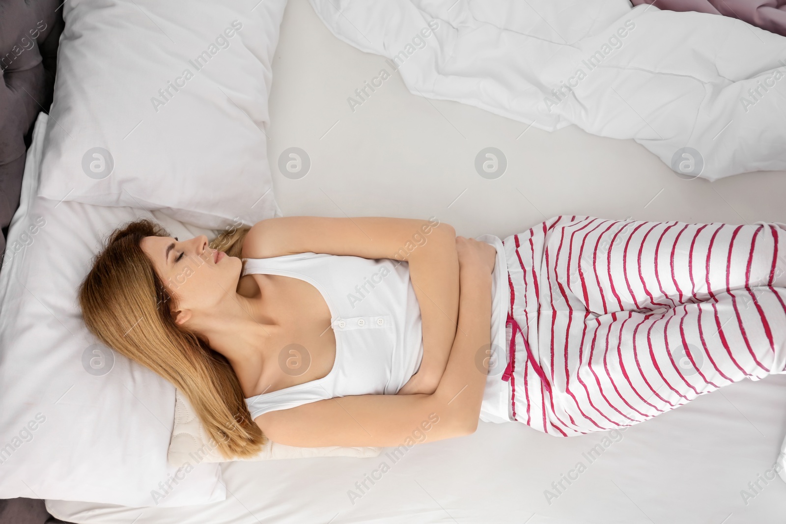 Photo of Woman suffering from abdominal pain in bedroom