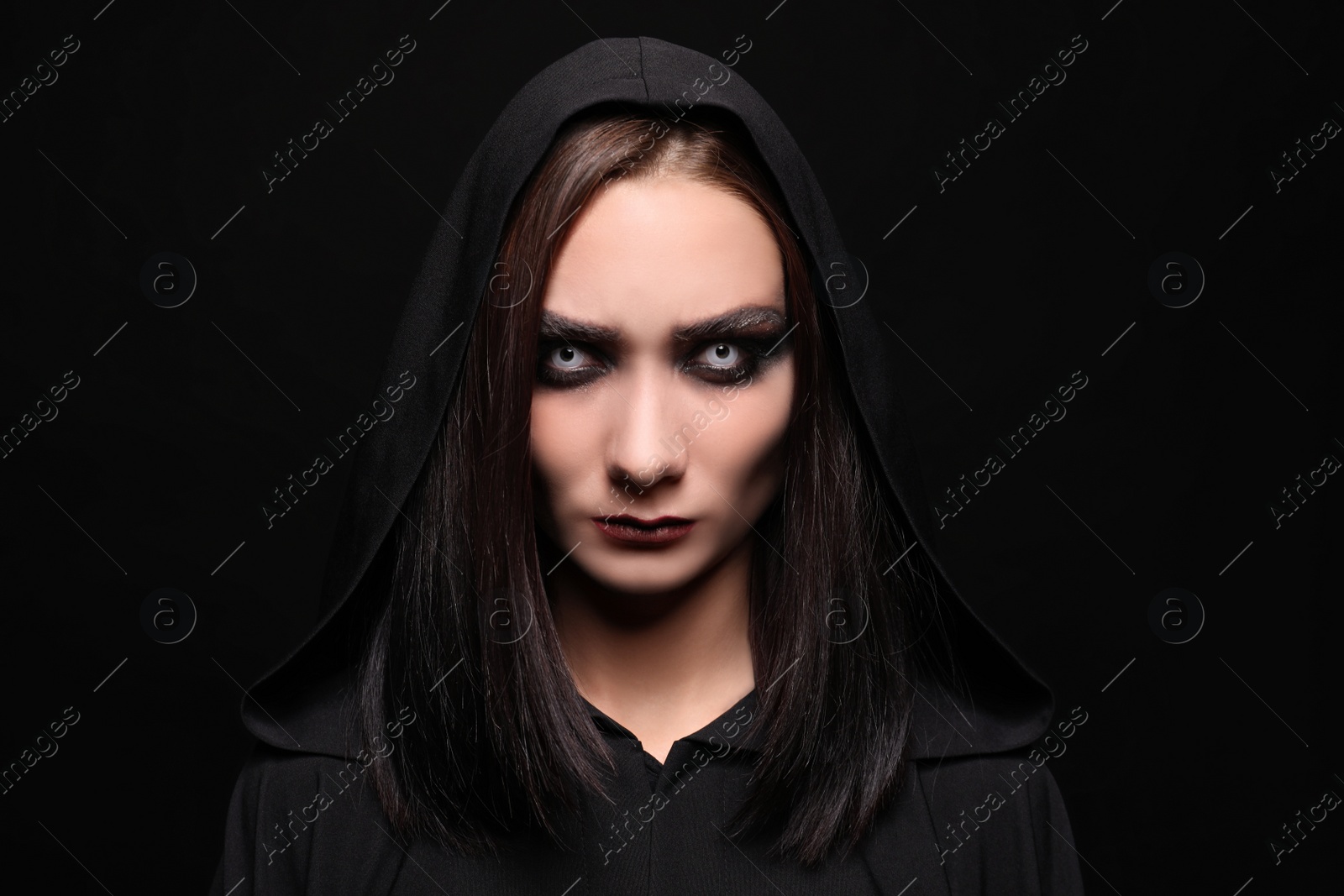 Photo of Mysterious witch with spooky eyes on black background