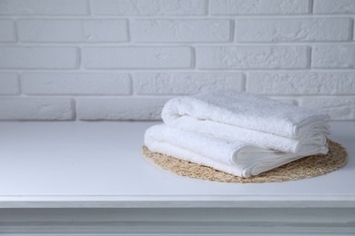 Photo of Clean towels on white table against brick wall, space for text