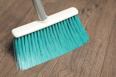 Photo of Sweeping wooden floor with plastic broom, closeup