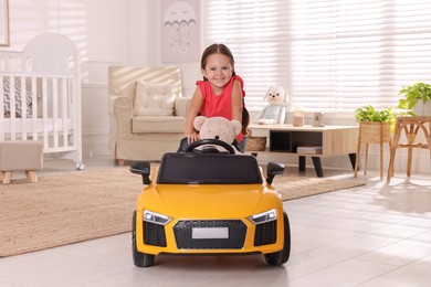 Adorable child with toy driving car in room at home