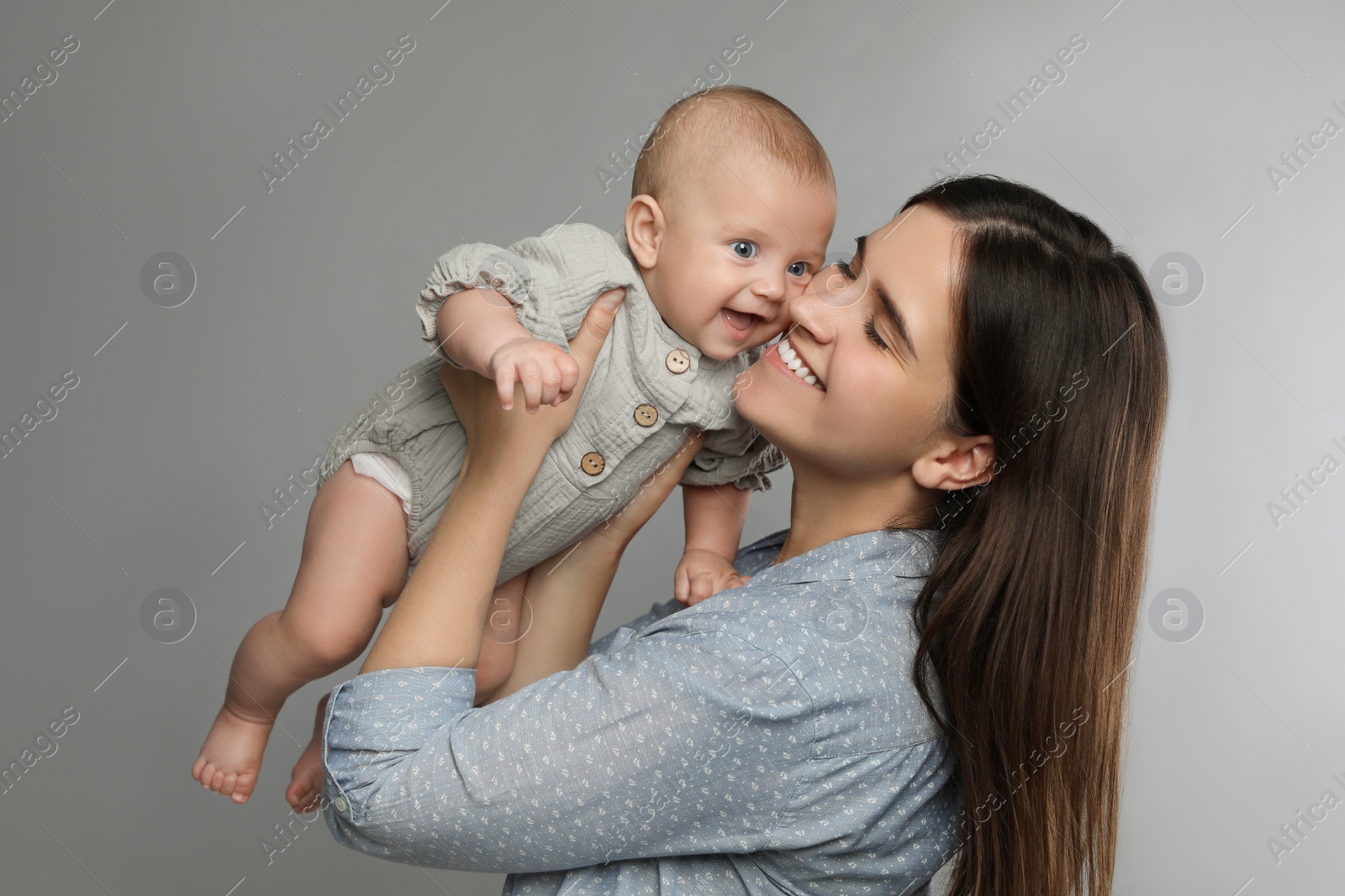 Photo of Beautiful mother with her cute baby on grey background