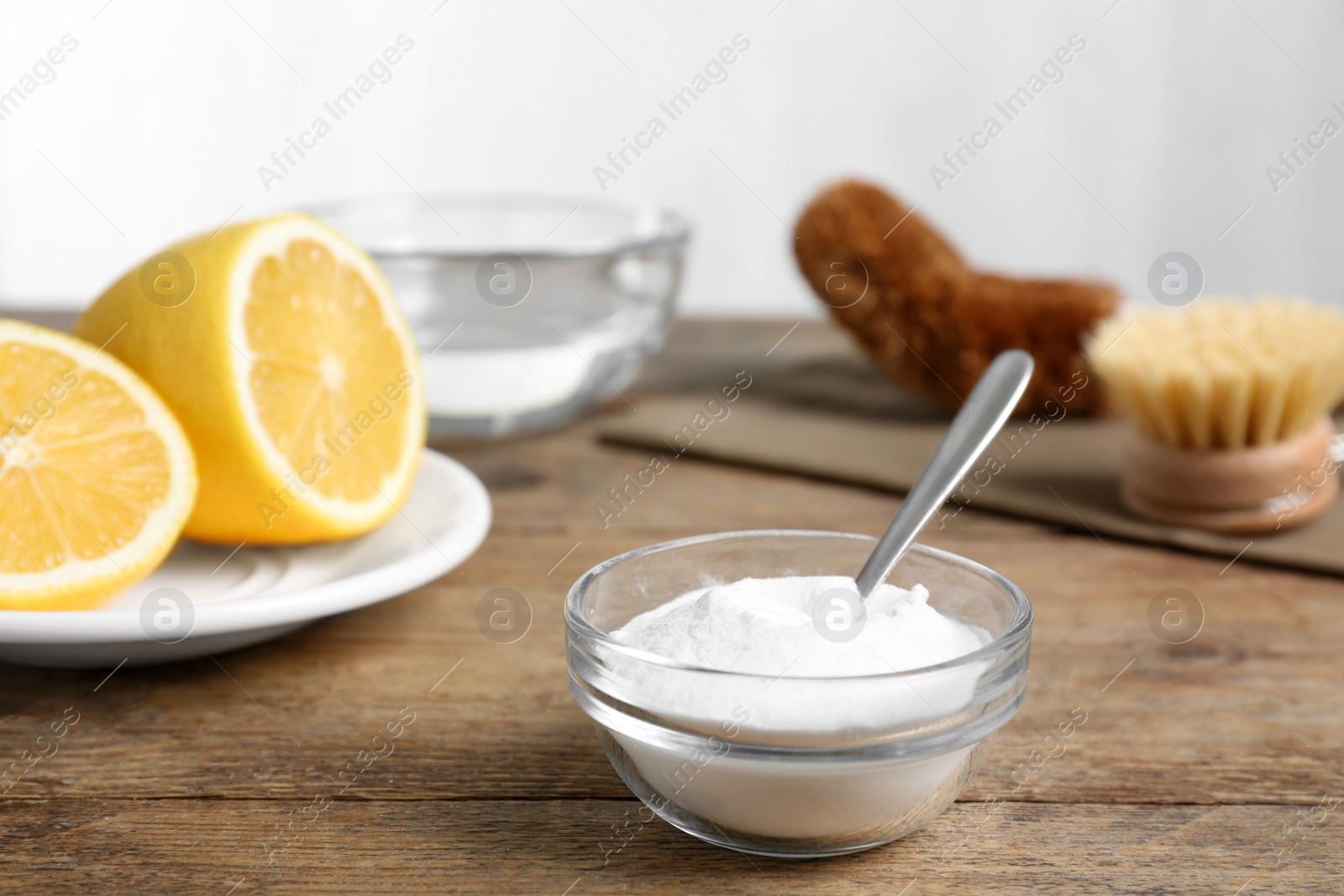 Photo of Baking soda in glass bowl on wooden table. Natural detergent