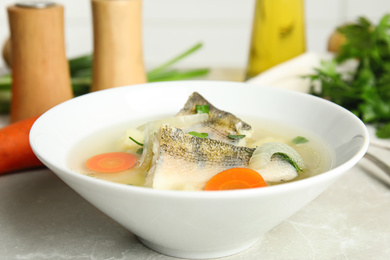 Delicious fish soup in bowl on light table, closeup