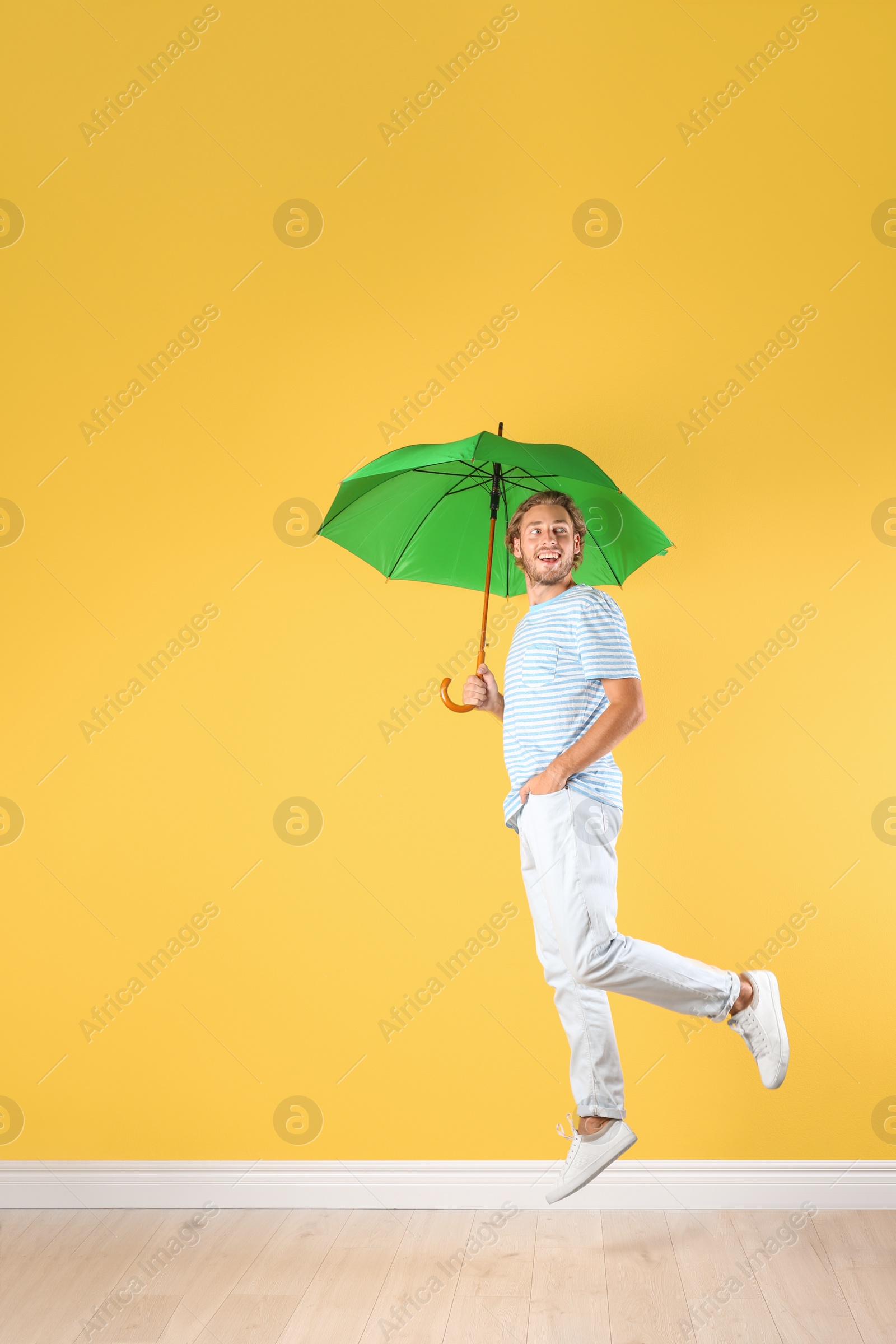 Photo of Man with green umbrella near color wall