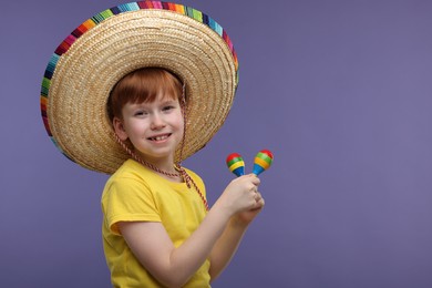 Cute boy in Mexican sombrero hat with maracas on violet background, space for text