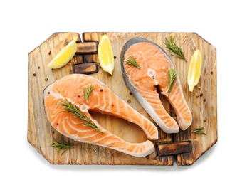 Wooden board with fresh salmon steaks and lemon on white background, top view