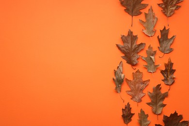 Photo of Dry autumn leaves on orange background, flat lay. Space for text