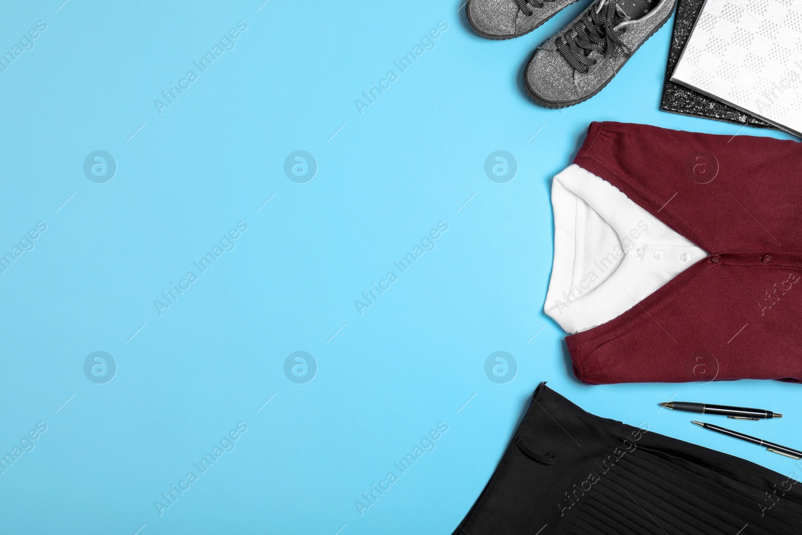 Photo of Flat lay composition with school uniform on blue background. Space for text