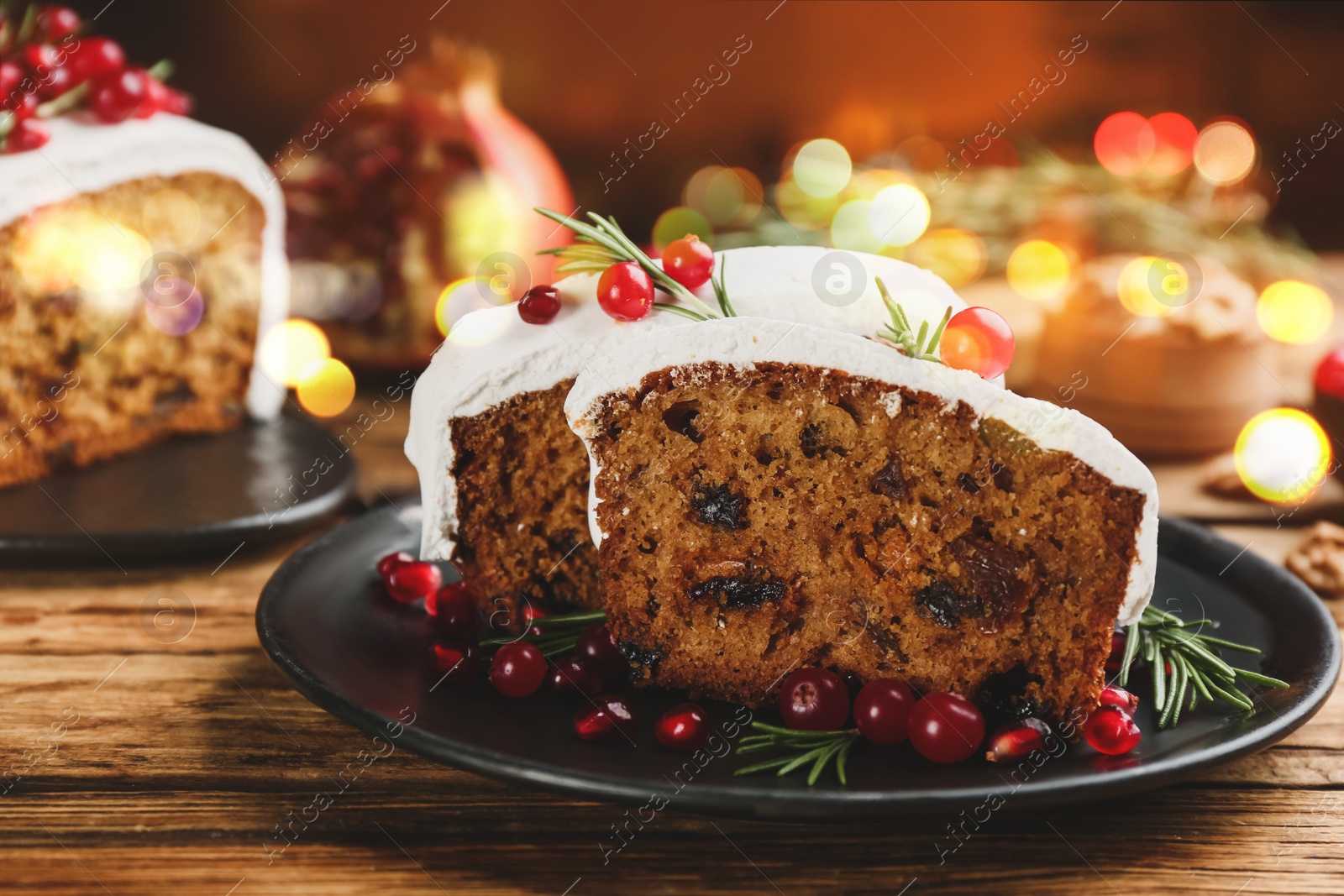 Image of Traditional classic Christmas cake decorated with cranberries, pomegranate seeds and rosemary on wooden table
