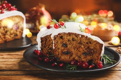 Image of Traditional classic Christmas cake decorated with cranberries, pomegranate seeds and rosemary on wooden table