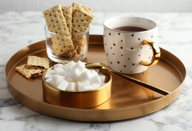 Photo of Refined sugar cubes in bowl and aromatic tea on white marble table