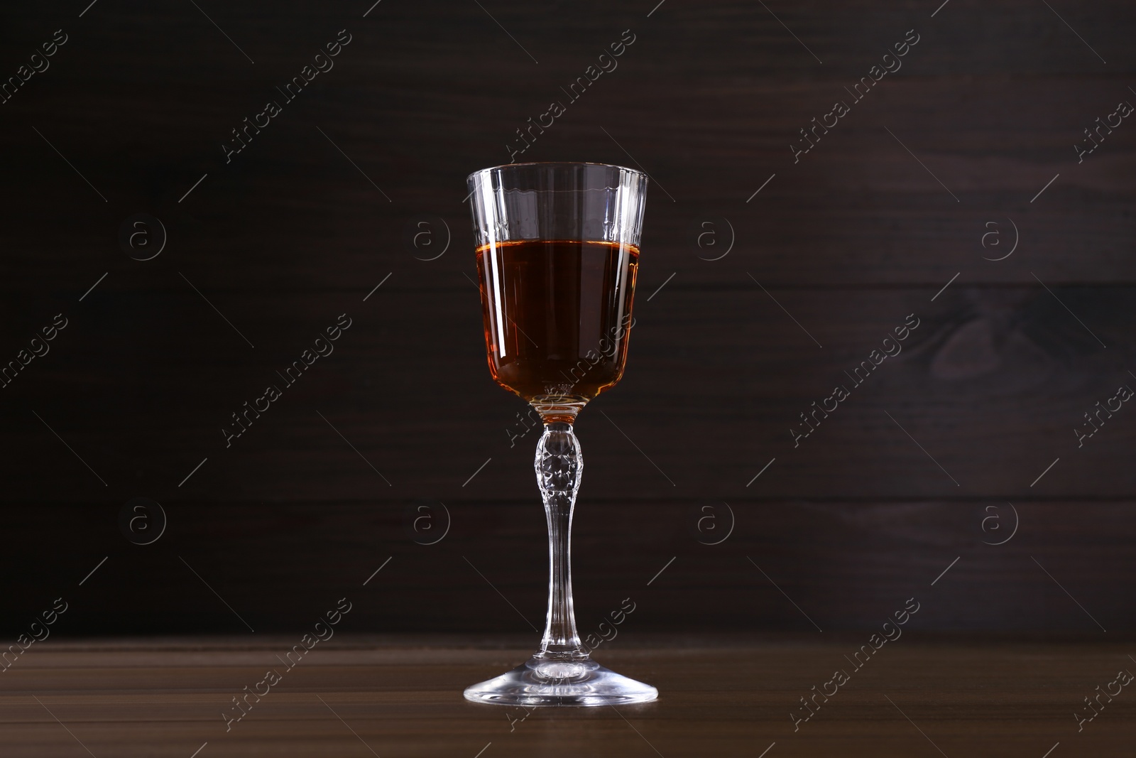 Photo of Delicious liqueur in glass on wooden table