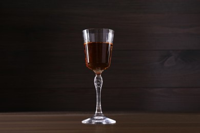 Delicious liqueur in glass on wooden table