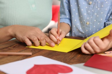 Photo of Little girl with her mother making beautiful greeting card at home, closeup