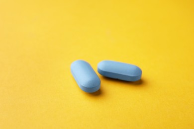 Photo of Two pills on orange background. Potency problem